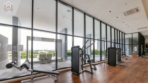 Ein modernes Fitnessstudio mit großen Fenstern, Holzboden und verschiedenen Trainingsgeräten.