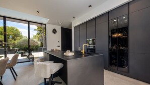 A modern kitchen with a large island, bar seating, and a view of the outdoors. - Villa Marro ZadarVillas (Privlaka)
