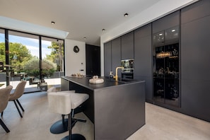 A modern kitchen with a large island, bar seating, and a view of the outdoors. - Villa Marro ZadarVillas (Privlaka)