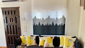 Una sala de estar con un sofá, una mesa de centro, un cuadro y una puerta.