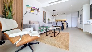 Un soggiorno moderno con un divano, una poltrona, un'area da pranzo e una cucina sullo sfondo.