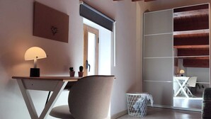 Een kamer met een bureau, stoel en raam.