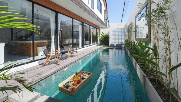 Ein modernes Haus mit Swimmingpool, Holzterrasse und Liegestühlen.