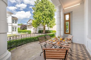 Ein Essbereich mit einem für das Frühstück gedeckten Tisch, einem großen Baum und Blick auf benachbarte Gebäude.