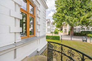 Ein weißes Gebäude mit einem holzrahmenfenster, einer Steintreppe und einem Metallgeländer.