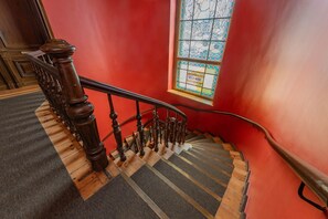 Un escalier en bois doté d’une rampe, de marches recouvertes de moquette et d’un vitrail portant l’inscription « VILLA MARIE ».