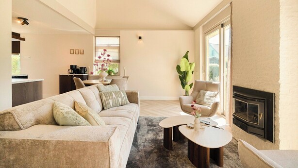 Un salon moderne comprenant un canapé, des fauteuils, une cheminée et un coin repas.
