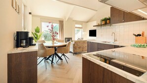 Une cuisine moderne avec un coin repas, des meubles en bois, une machine à café et un téléviseur.