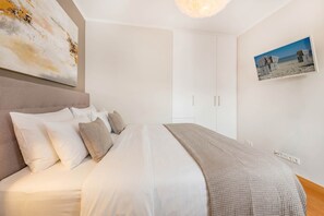Une chambre à coucher avec un lit, une tête de lit, un tableau accroché au mur et un luminaire fixé au plafond.