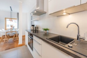 Une cuisine moderne dotée d’un plan de travail noir, d’appareils électroménagers en acier inoxydable et d’un grand évier.