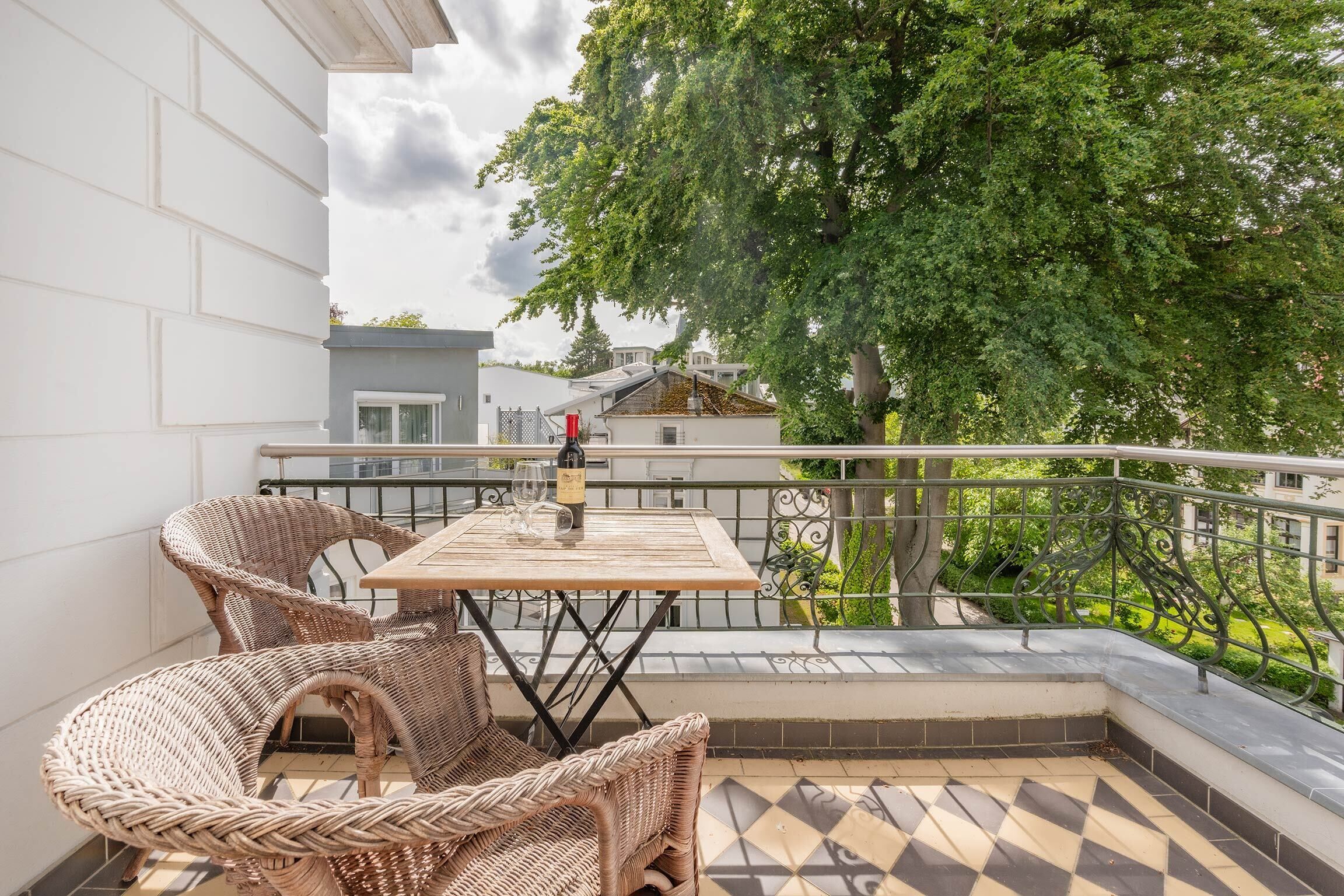 Een balkon met rieten meubels, een tafel en een fles.