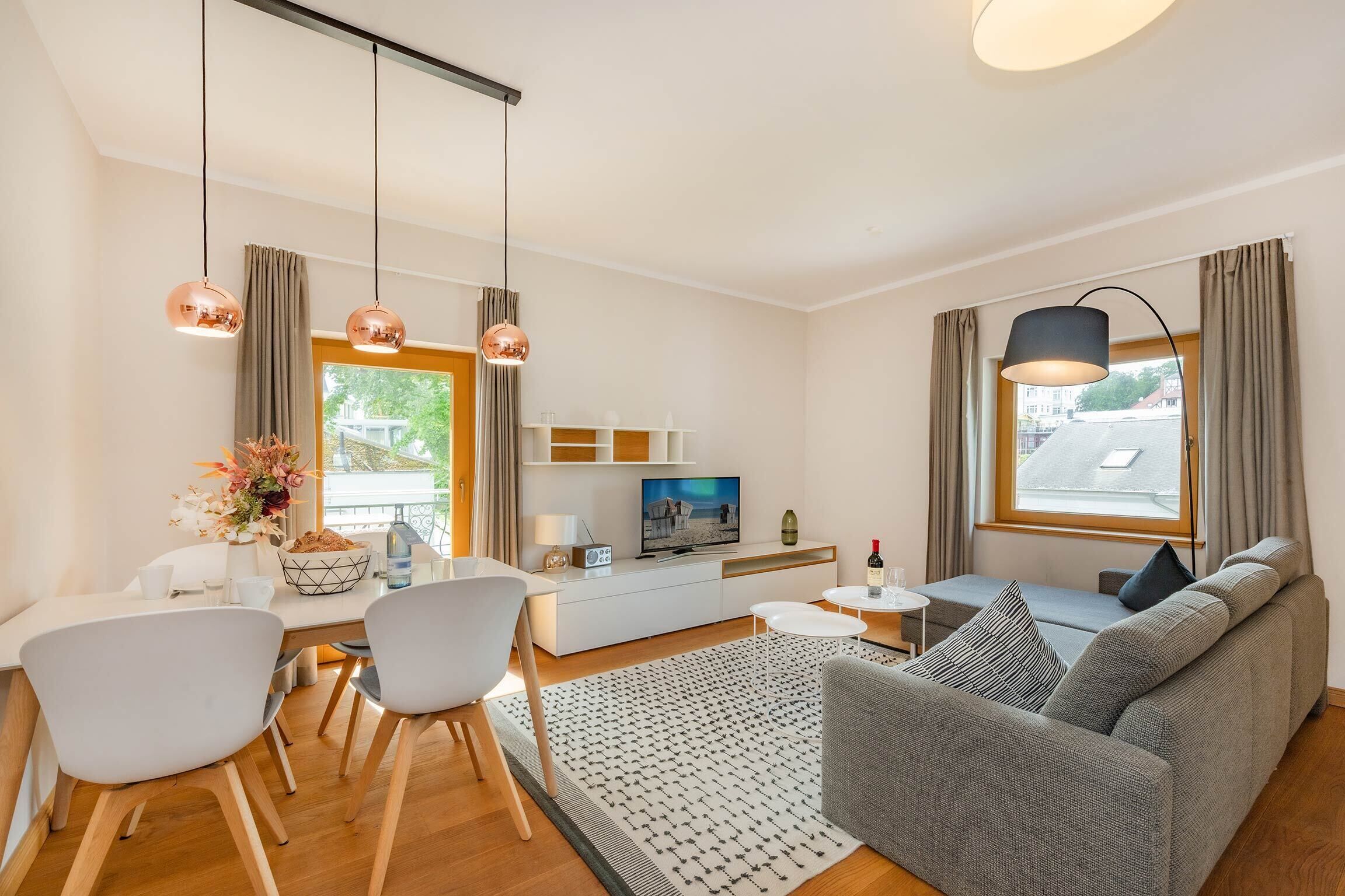 Un salon moderne comprenant un canapé, une table à manger, des chaises et un téléviseur.