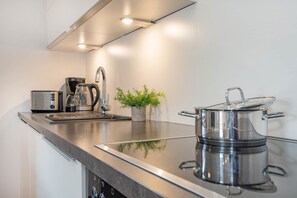 Une cuisine moderne avec un plan de travail en acier inoxydable, une machine à café, un grille-pain et une casserole sur la cuisinière.