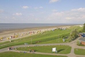 Eine Küstenlandschaft mit Strand, Wiesen und einigen Gebäuden.