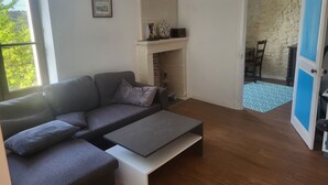 En stue med sofa, sofabord, pejs og en dør til et andet rum.