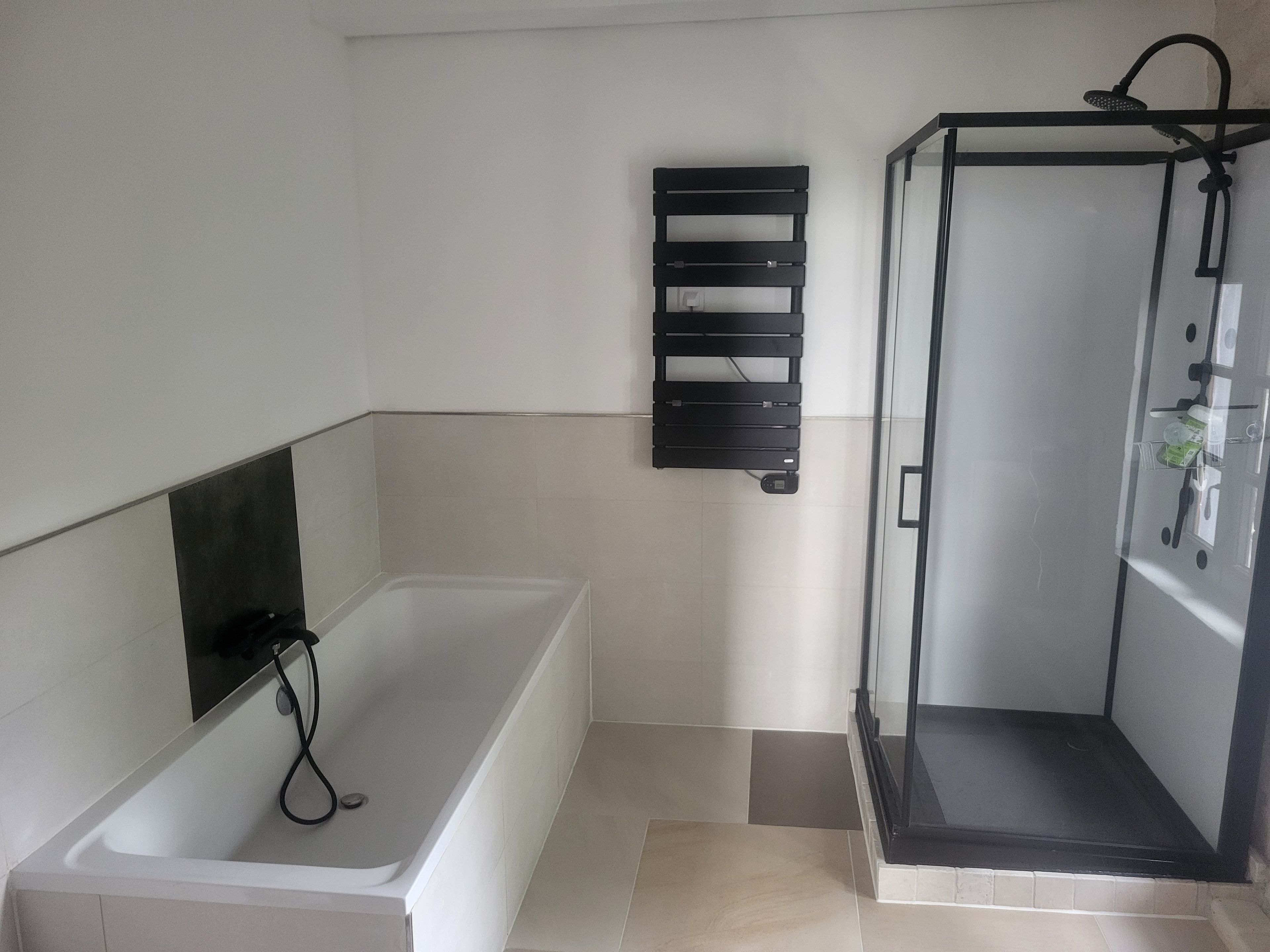 Une salle de bain moderne équipée d’une baignoire, d’un espace de douche et d’un porte-serviettes.