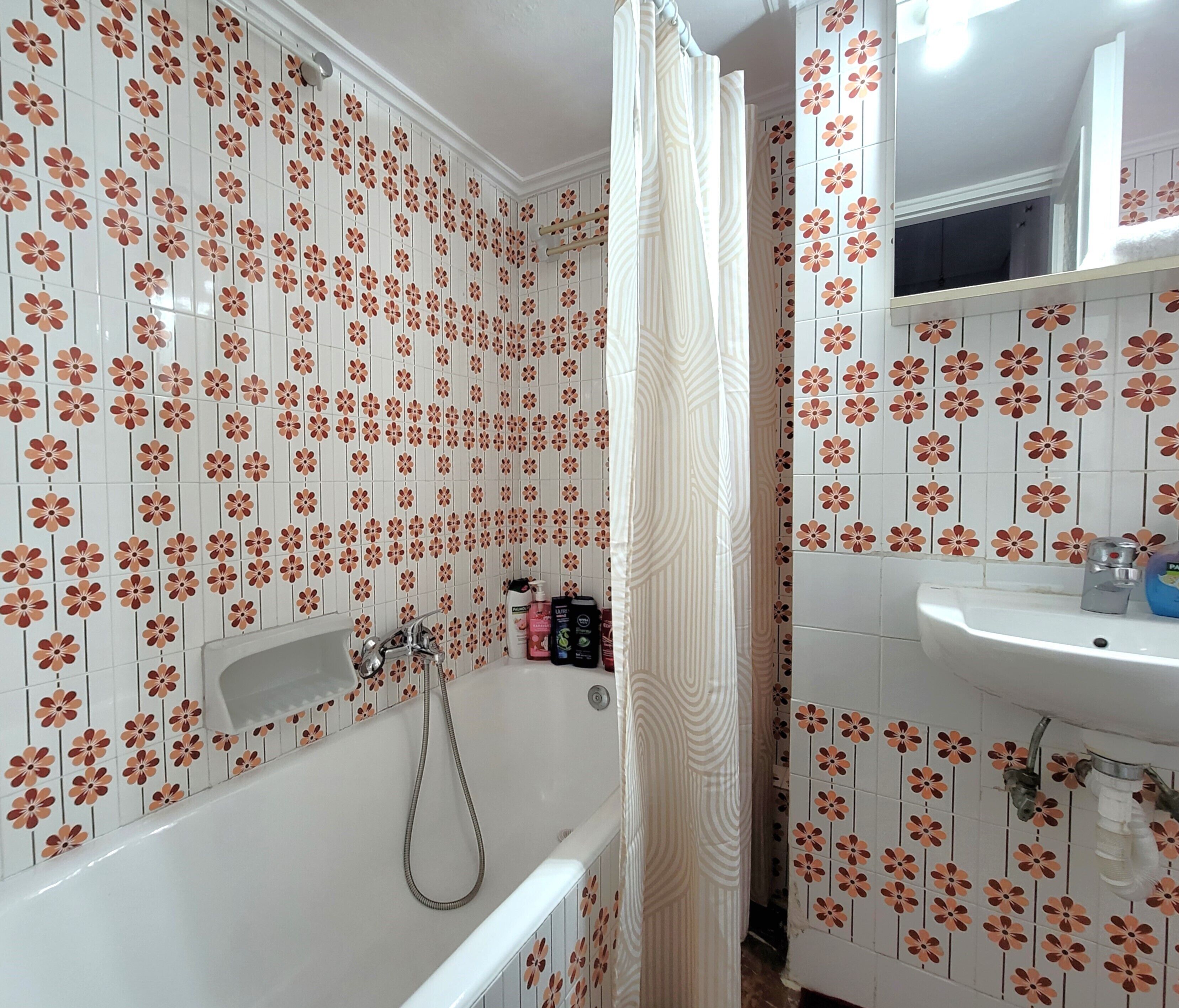 Un baño con ducha, lavamanos y espejo.