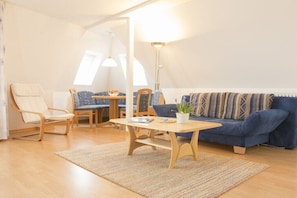 Ein gemütliches Wohnzimmer mit einem blauen Sofa, einem Holztisch und einem Sessel.