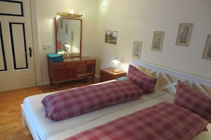 Ein Schlafzimmer mit Bett, Schminktisch, Spiegel und Nachttisch.