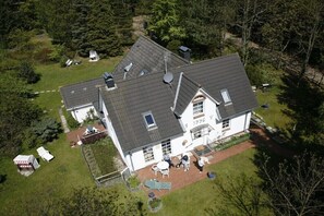 Ein großes Haus mit geneigtem Dach, mehreren Satellitenschüsseln und einem gepflegten Rasen.