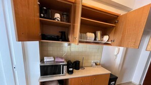 A compact kitchen with wooden cabinets, a microwave, a kettle, and a coffee maker. - Residence City Escape 202 (Rhodes)