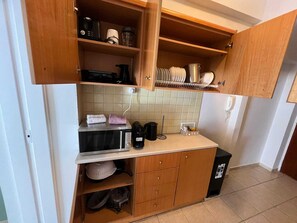 Eine kleine Küche mit Holzausstattung, einer Mikrowelle, einem Wasserkocher und einer Kaffeemaschine.