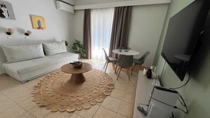 A modern living room with a sofa, coffee table, dining area, and a flat-screen TV. - Residence City Escape 202 (Rhodes)