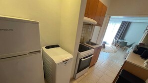 A compact kitchen with a refrigerator, a washing machine, an oven, and a sink. - Residence City Escape 202 (Rhodes)