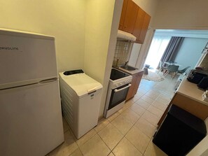 Eine kleine Küche mit Kühlschrank, Waschmaschine, Backofen und Spüle.