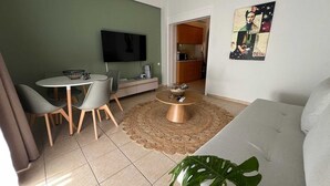 A living room with a TV, dining table, chairs, a coffee table, and a plant. - Residence City Escape 202 (Rhodes)