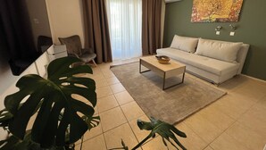 Una sala de estar con sofá, mesa de centro y una planta grande.