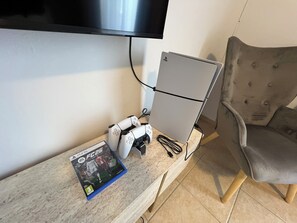 Ein Gaming-Einrichtung mit einer PlayStation 5, einem Spiel und einem Monitor auf einem Schreibtisch.