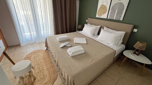 Una habitación de hotel con cama, mesita de noche, lámpara, aire acondicionado instalado en la pared y una obra de arte.