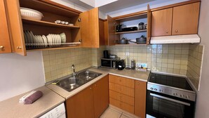 Una cocina compacta con armarios de madera, un lavamanos de acero inoxidable, un microondas, una estufa y un lavavajillas.