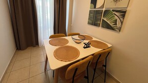 Un comedor con una mesa, sillas y un ventanal con cortinas.