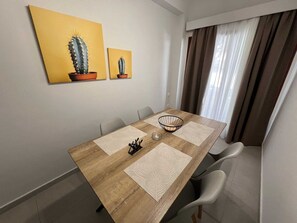 Ein Essbereich mit einem Holztisch, vier Stühlen, einem Kerzenhalter und zwei Kakteenbildern an der Wand.