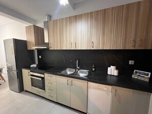 Eine moderne Küche mit Holzschränken, einer schwarzen Arbeitsplatte, einem eingebauten Backofen und einem Geschirrspüler.