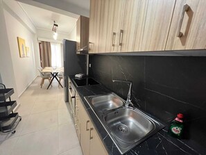 A modern kitchen with black marble countertops, stainless steel sinks, and wooden cabinets. - Residence City Skippers 205 (Rhodes)