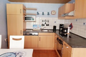A compact kitchen with wooden cabinets, a microwave, a sink, and a coffee maker. - Little Seal Paradise (Moorweg)