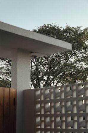 Una construcción de concreto con puerta de madera y valla de celosía blanca.