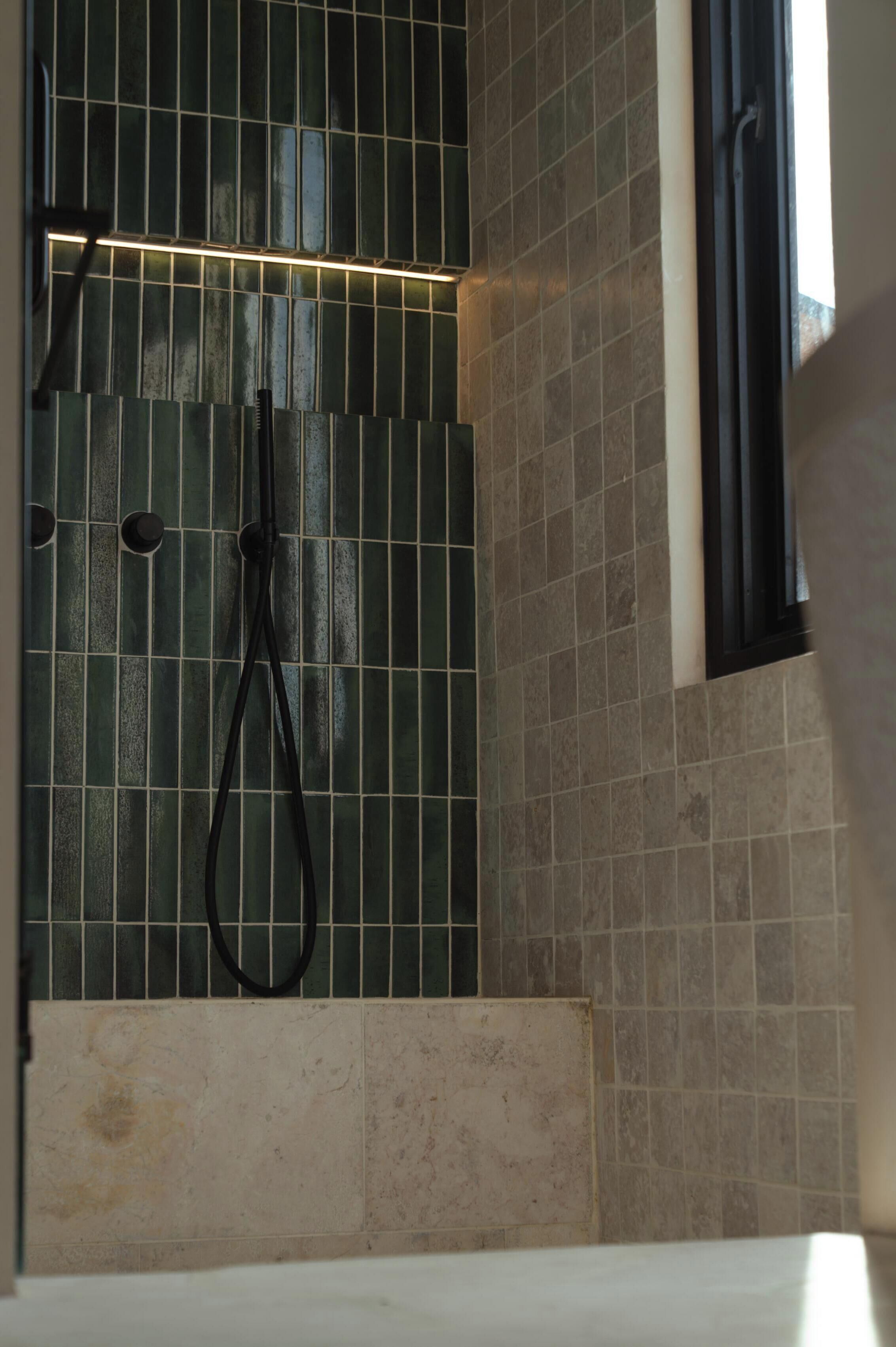 A bathroom with a shower area, tiled walls, and a bathtub.