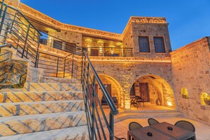 Un edificio de piedra con escaleras, asientos exteriores y un comedor.