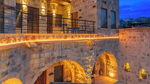Un edificio de piedra con balcón, arcos y asientos al aire libre.