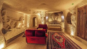 Una habitación con pared de piedra, sofá rojo, alfombra estampada y puerta de madera.