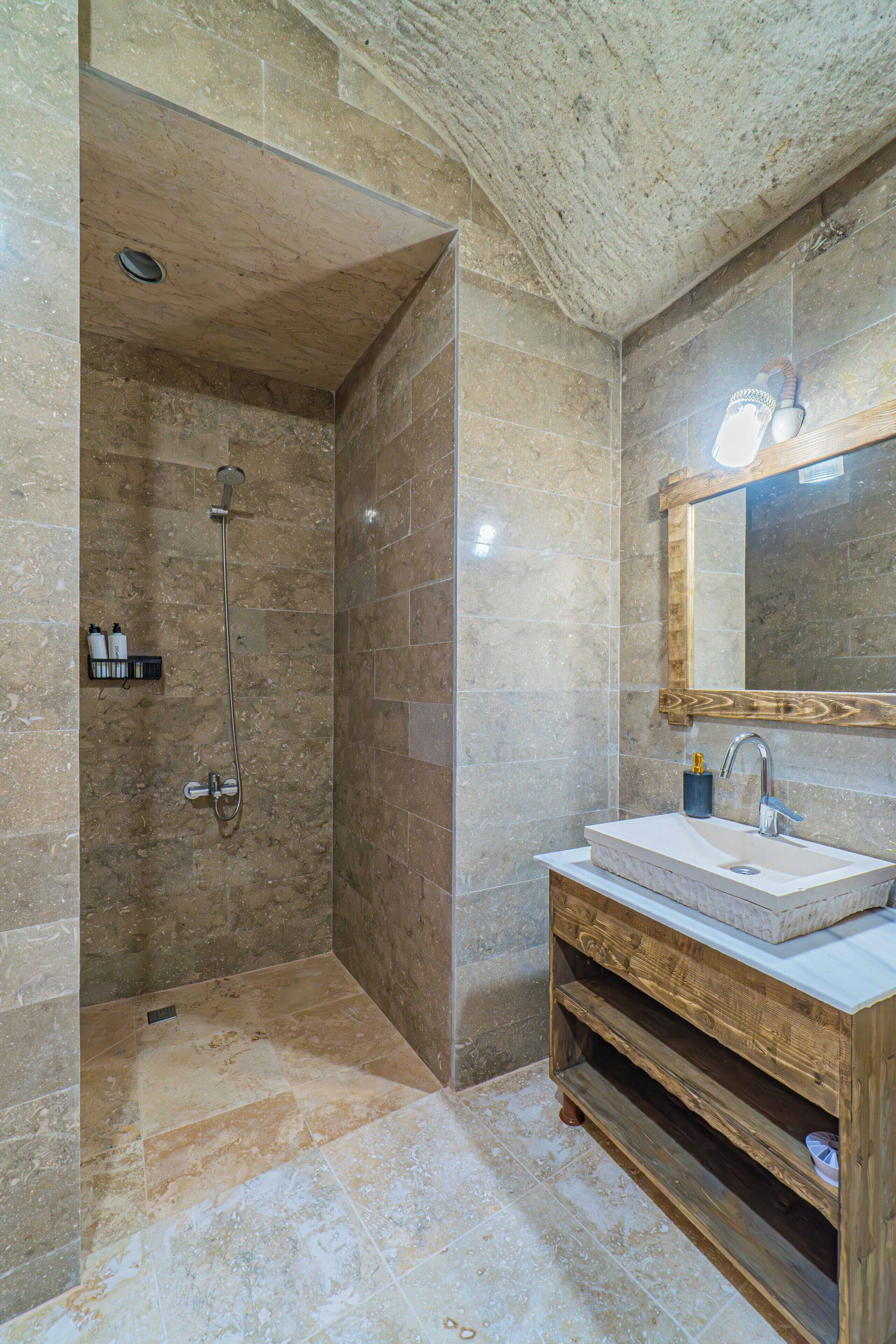 Ein Badezimmer mit Dusche, Waschbecken, einem Holzkosmetikschrank und einem Spiegel.
