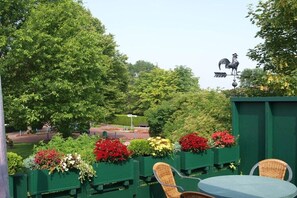 A patio area with green planters, wicker chairs, and a round table. - Sturkenhues OG holiday apartment (Horumersiel)