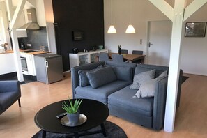 Ein stilvoller Wohnbereich mit einer Couch, einem Couchtisch und einer Küchenzeile.