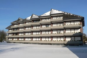 Ein mehrgeschossiges Gebäude mit einer symmetrischen Fassade, mehreren Balkonen und einem flachen Dach.