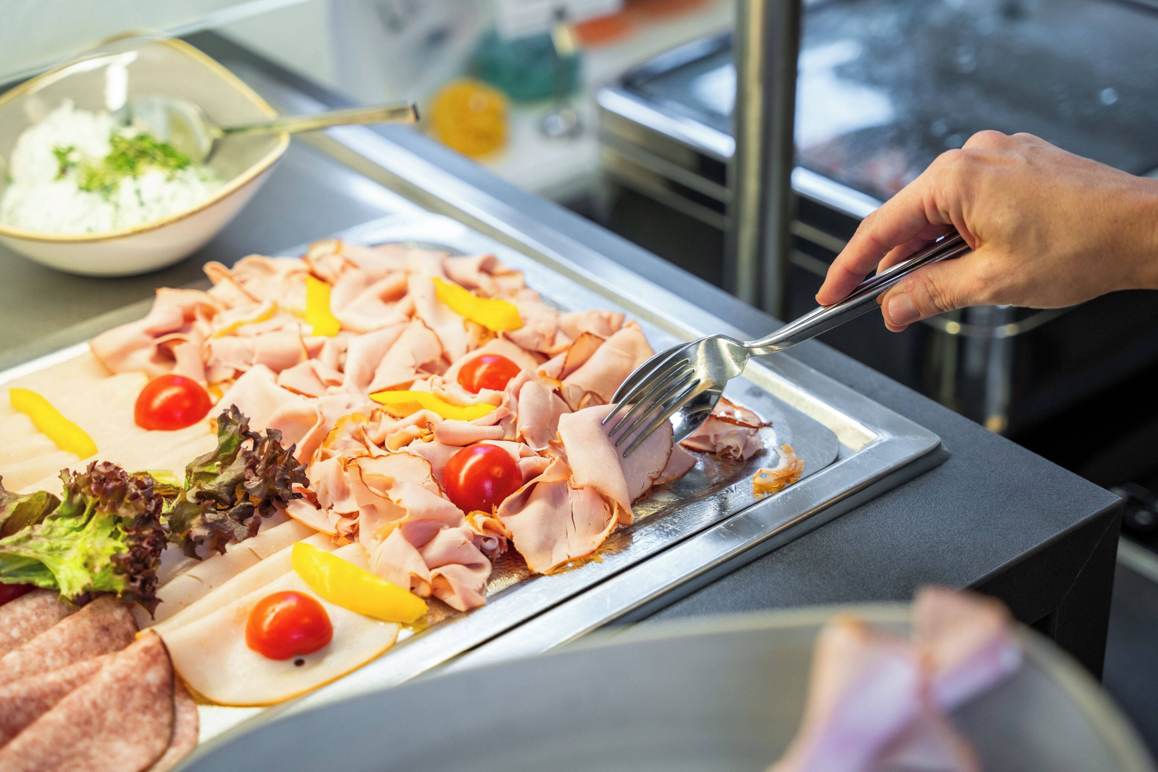 A buffet with various meats, vegetables, and a bowl of salad.