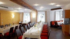 A dining area with long tables, chairs, and a kitchen area. - Hotel Wesenufer (Wesenufer)